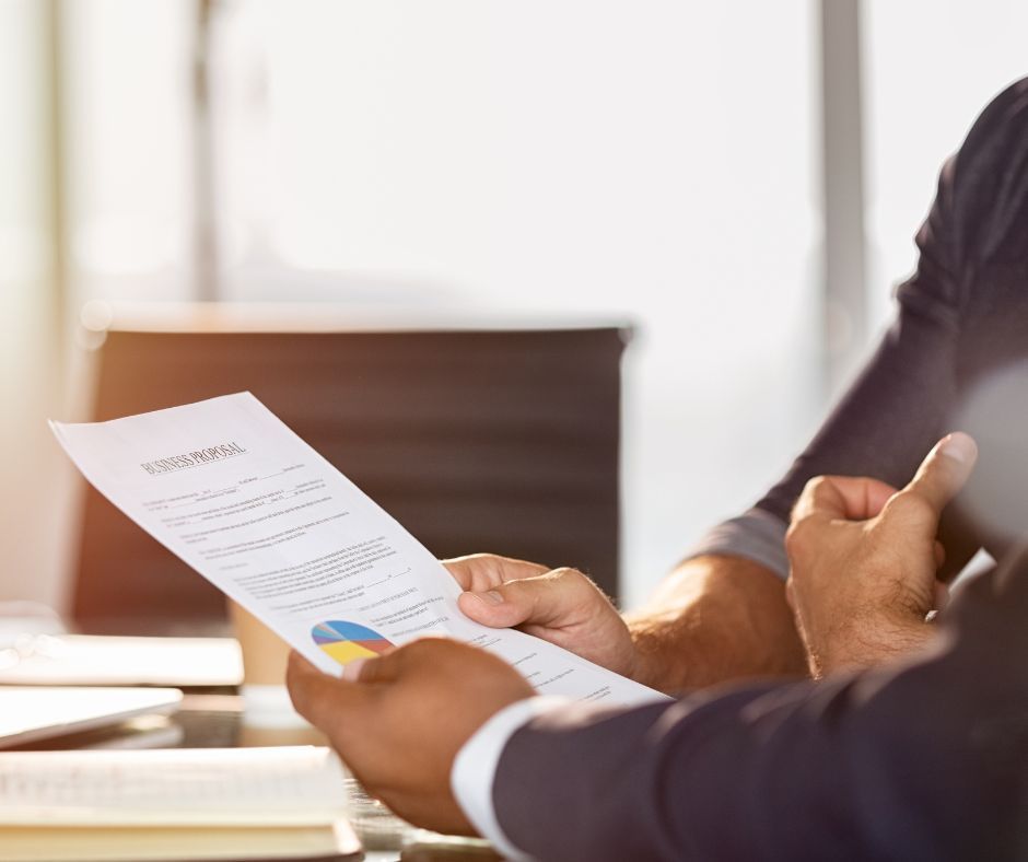 Two people reviewing business report with charts and data, in office setting.